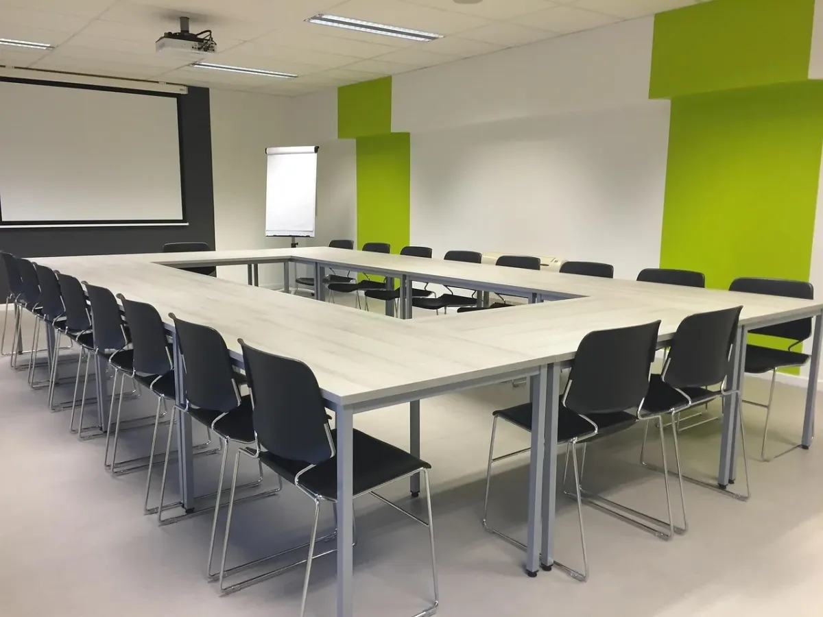 Nowoczesna sala konferencyjna z ekranem projekcyjnym przygotowana do profesjonalnego spotkania biznesowego.